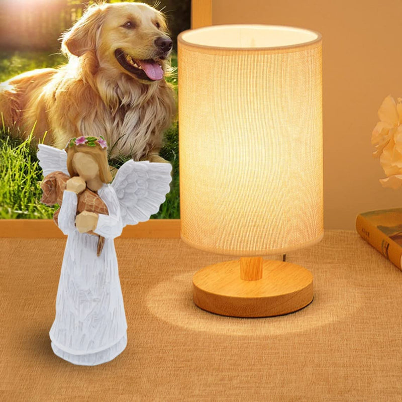 a picture of dog next to a lamp and agel figurine holdig dog figure on table